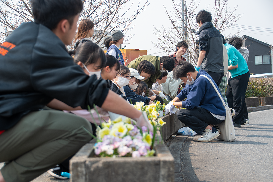 道端で花を植える活動に参加する人々が集まっている