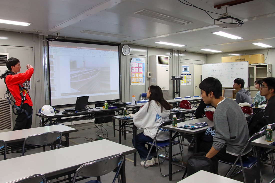 プロジェクターを使った説明を受ける学生たち