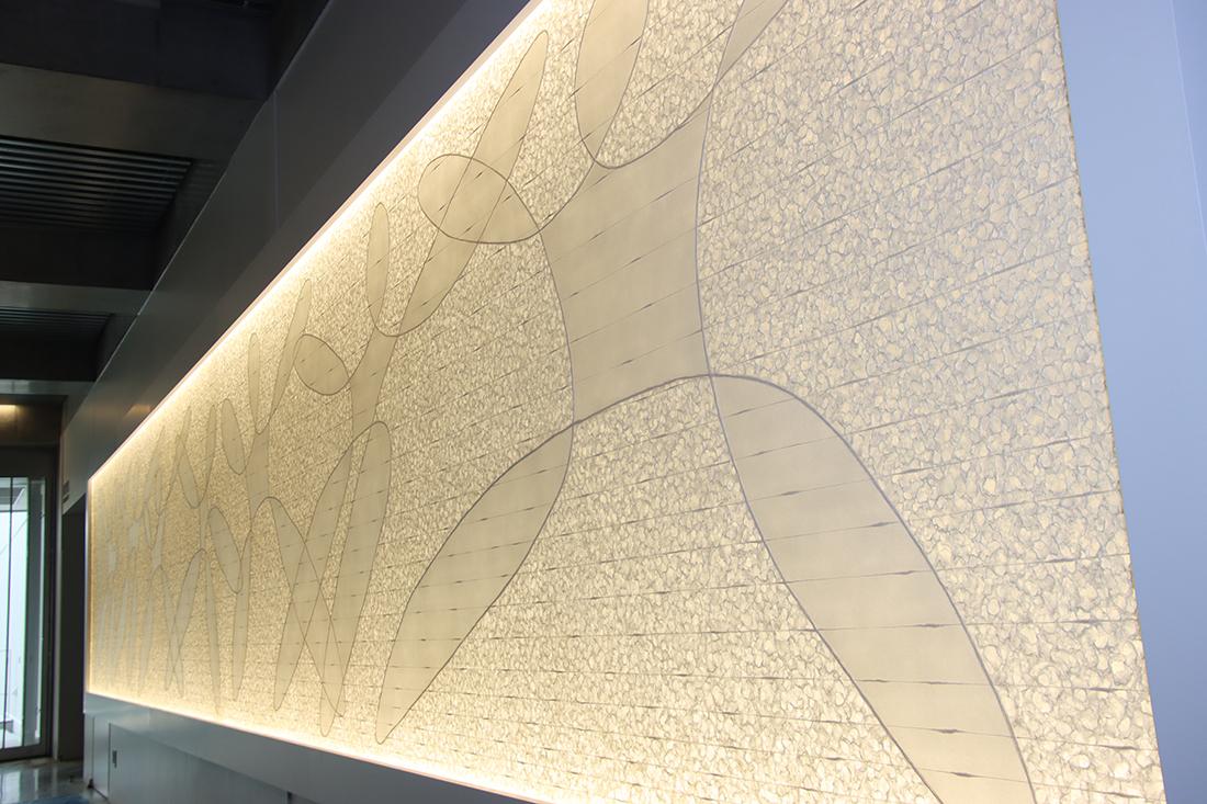 長い通路の壁に、抽象的な曲線模様の大きな壁面アートが設置されている