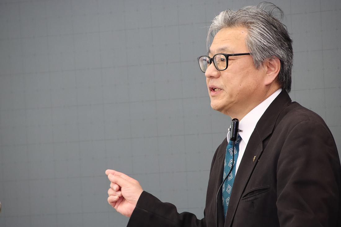 黒板の前で講演する男性