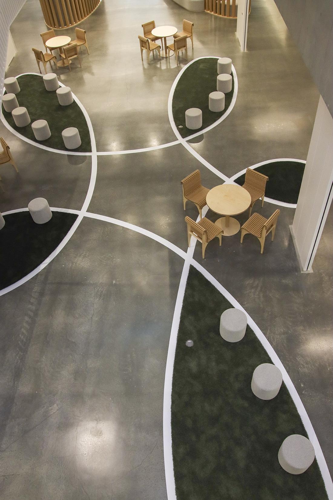 ラウンジの俯瞰。丸テーブルと椅子、円筒形スツールが点在している